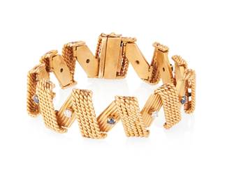 1003
A 14K Gold, Sapphire and Diamond Bracelet
Featuring a zig-zag design of twisted and striped gold accented by alternating round sapphires and diamonds
Length: 7 3/4 in., 7/8 in. wide
71.1 grams gross
Estimate: $2,500 - $3,500