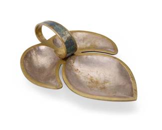 1137
Mid-20th century; Taxco, Mexico
A Los Castillo silvered brass bowl
Marked to underside: Los Castillo Taxco / Handwrought / Hecho en Mexico / 250
The three-compartment foliate-form bowl with handle inlaid in green and blue hardstone
4.875" H x 16.625" W x 12.375" D
Estimate: $200 - $400
