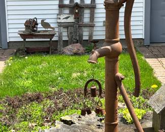 cast iron water well pump, with a wind chime and primitives in the background