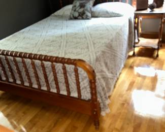 Wood spindle bed frame with side table on the right.