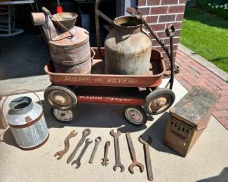 Couple radioFlyer wagons, primitive milk containers, on the right is a 20 mm ammo box from 1970 and various vintage hand wrenches.