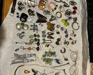 Assortment of costume jewelry - earrings, necklaces, a watch and a pair of elegant gold tone glasses.