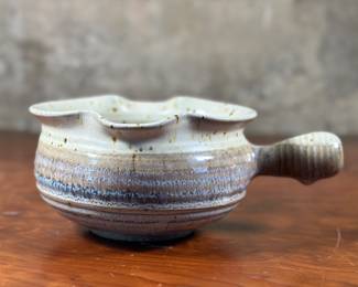 This lot features a studio pottery bowl, handmade by Blue Spruce Pottery in Bend, Oregon circa 1988. This item measures, 3.75” H x 7” W x 9.5” D. Michael and Michele Gwinup established Blue Spruce Pottery in Bend Oregon in 1976. Their stoneware pottery are all functional pieces that are food safe. It is fired in a gas kiln to 2200 degrees, cone 10. This makes the clay very durable. Maker mark underneath as shown in photos.