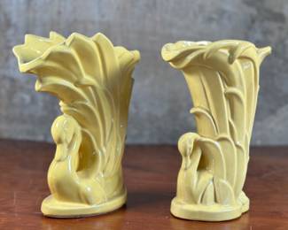 This lot features a pair of McCoy swan vases, circa 1930s. A matching pair with maker mark underneath as shown in photos. Both are in good overall condition. One has a small chip present shown in photos. Each vase measures, 9” H x 4.25” W x 7” D. McCoy Pottery, established in 1899 by James W. McCoy, evolved from a family-run business to a major player in the American pottery industry, ultimately closing in 1990. The company, known for its functional stoneware and later art pottery, experienced several ownership changes and name alterations, including the Nelson McCoy Pottery Co. in 1933. Key milestones include the merger with Brush Pottery in 1911, forming Brush-McCoy Pottery. The company also faced challenges, including a major fire in 1950. Despite changing hands and facing economic shifts, McCoy Pottery remained a popular and recognizable name for its quality and unique designs, particularly its art pottery lines.