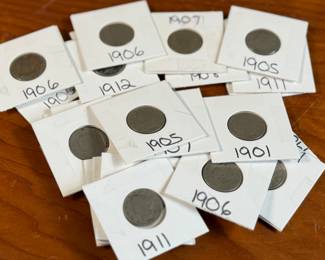 This lot features twenty-four (24) “V” nickels from various years, kept in protective slips. The “V” nickel, officially called the Liberty Head Nickel, was a U.S. five-cent coin minted from 1883 to 1912, with a few produced in 1913. It earned its nickname due to the large Roman numeral “V” on the reverse, representing the coin’s denomination. The coin was designed by Charles E. Barber, the U.S. Mint’s Chief Engraver.