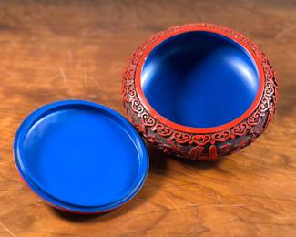 This lot features a vintage Chinese lacquered red Cinnabar jar, circa 1970s. This piece measures, 4” H x 8” W x 8” D. A cinnabar jar is a decorative Chinese art piece, often a ginger jar or vase, that features a red lacquer finish, typically carved with intricate designs. The “cinnabar” in this case refers to the red lacquer itself, not the mineral cinnabar (mercury sulfide). The lacquer is applied in multiple layers and then carved to reveal the underlying designs.
