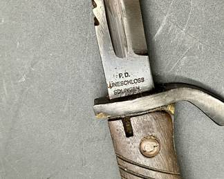 P.D. Luneschloss in Solingen, Germany. The blade is made of steel and features a sawback design. The handle is made of wood and has grooves for a better grip. The bayonet is designed to be attached to a rifle, likely a Mauser rifle, and used in close combat. Bayonets of this type were commonly used by German soldiers during World War I and World War II.