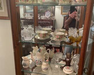 Curio in dining room full of china tea sets figurines and crystal