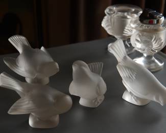 A set of four Lalique frosted crystal sparrows in various poses, and a set of Lalique crystal lion head lighter and cigarette holder