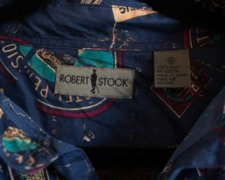 Closeup of vintage Robert Stock men's silk short-sleeve button front shirt, dark blue with retro "travel" print pattern of luggage labels and hotel signs