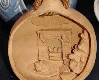 Italy terracotta ornament featuring a cozy Christmas scene, complete with a fireplace, stockings, a sleeping cat, and presents.