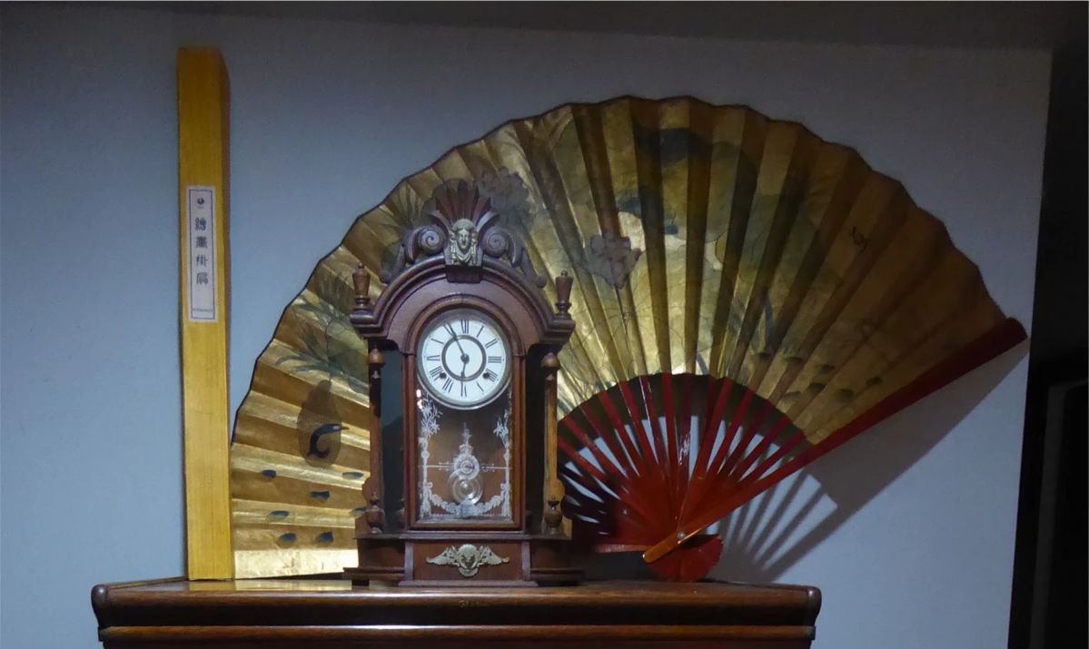 Antique Triumph Clock Wood case; side mirrors with wood finials; original keys and pendulum; 2 ft H; 17 in. W; 6 in. D Chinese Fan Wall Décor 40” H; 69” W