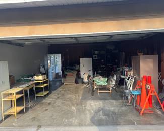 Garage is Full Refrigerator Chair Antique Rolling Carts White Metal Cabinet Roaster Vintage License Plates Pepsi Crate Schaefer Beer Box Vintage Saw Table Full of Tools and Tool Chests Orange Orange Caution Sign and Plastic Cones