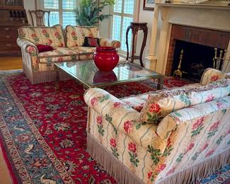 Pair of custom upholstered loveseats, red oriental rug, and brass and glass coffee table