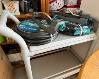 Garden hoses and accessories - Collection of coiled hoses and watering equipment on white shelf