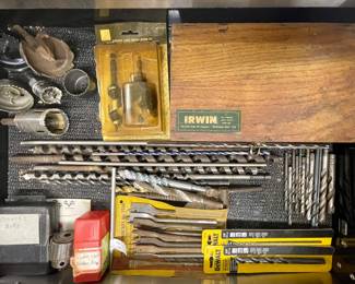 A wide assortment, including auger bits, masonry bits, and general-purpose twist hole saw drill bits, some in their original packaging from brands like Irwin and DeWalt.