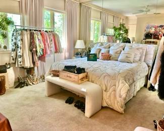 SPACIOUS MASTER BEDROOM WITH 2 CLOTHES RACKS, TABLE FULL OF HANDBAGS, AND A LARGE BATHROOM WITH 2 FULL CLOSETS.