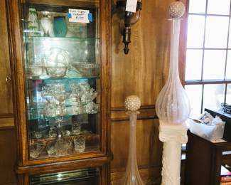 Narrow wood curio cabinet. Pair of tall glass vase/urns with round toppers