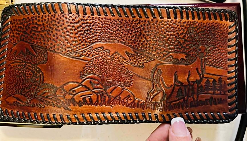 This is a 1950’s - 1970’s vintage hand-tooled leather wallet featuring a fly fishing scene.
