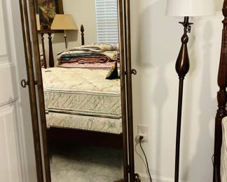 This is a wrought iron cheval mirror with decorative scrollwork.
