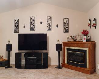 Samsung smart TV with speakers, vintage wall decor and portable fireplace.