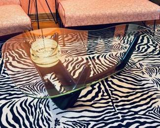 Amazing 1950’s biomorphic glass top coffee table with black wood book storage base. There are some small chips to the glass