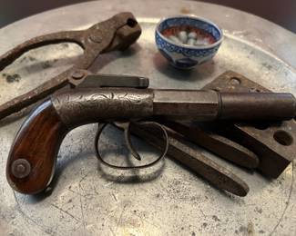 19th century pre-Civil War single shot pistol by Bacon & Co, polished wooden grips decorated with chased and engraved metal work. This tiny pistol was small enough to fit into a lady’s pocket or reticule and was frequently called the “Hooker’s Friend”. Shown with antique bullet molds.