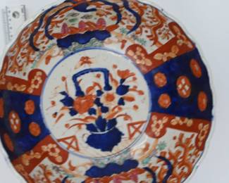 A bold and expressive Imari porcelain bowl featuring scalloped rim and richly painted interior panels in cobalt blue, iron red, and gold. Hand-painted floral sprays and stylized medallions alternate with abstract figural forms. Estimated date: 1830-1860