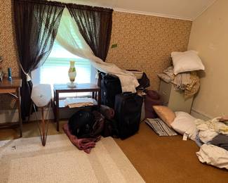 bedding, file cabinet, luggage, albums, small table, lamp, area rug