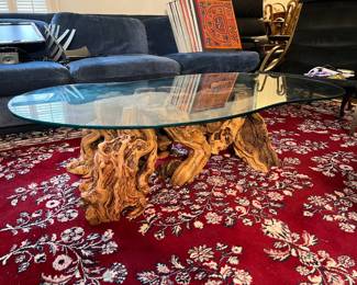 This similarly-styled coffee table includes the glass-top and a driftwood base. There's a different rug underneath this one!