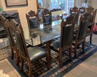 This dining table is also topped with glass, but the base is different. Also, there are eight matching chairs in the set.