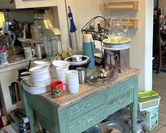 The main item here seems to be the vintage, distressed table with drawers, along with the kitchen appliances and utensils.