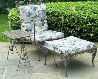 (3pc) Vintage Wrought Iron Armchair, Footstool & Side Table #1 | Wrought iron outdoor/patio furniture, including a armchair, matching footstool, and rectangular side table, all with floral designs along the edges. Similar to Woodard Furniture designs. Chair and footstool include cushions. Footstool: h. 12 x w. 22 x d. 24. Table: h. 19.5 x w. 12.5 x d. 18.5 - h. 37 x w. 28 x d. 28 in (Chair)