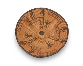 302
A polychrome Apache pictorial basketry tray
Early 20th century; Southwest United States
A coiled shallow basket with raised center mound, featuring multiple standing figures amid three dotted radiating stepped motifs
3.875" H x 13.25" Dia.
Estimate: $600 - $900
