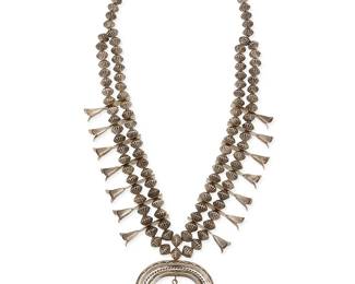325
A Southwest sterling silver and turquoise squash blossom necklace
Mid/late 20th century
Unmarked
Featuring a three-wire silver naja with stamped motifs and set turquoise, with fourteen silver blossoms suspended from two strands of textured ridged silver beads
26" L x 3" H
146.7 grams gross
Estimate: $500 - $700