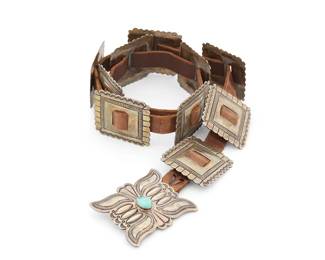 318
A Navajo sterling silver concho belt
Late 20th century, Diné
Stamped to buckle verso: Tc / Sterling [for Toni Curtis or Tommie Charlie, Navajo]
Comprising a rectangular stamped silver buckle with central set turquoise, and ten smaller conchos with stamped edging, all mounted to a brown leather strap
Buckle: 2.5" H x 3" W; each concho: 2.125" H x 2.375" W; strap: 34.5" L x 0.75" H
362.2 grams gross
Estimate: $1,000 - $2,000