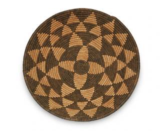 310
An Apache basketry tray
Early 20th century; Southwest United States
A coiled wide tray with concentric bands of radiating negative dark and light triangle floral motifs
3" H x 14" Dia.
Estimate: $400 - $600