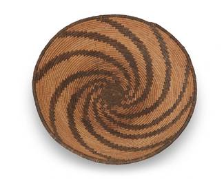 309
An Apache basketry tray
Early/mid-20th century; Southwest United States
A coiled wide tray with multiple swirling rays issuing from the center
3.5" H x14" Dia.
Estimate: $200 - $400