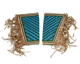 25
A pair of Plateau-style beaded gauntlet cuffs
Late 19th century; Northwest United States
Two beaded tapered cuffs with allover blue and black stepped design edged by rows of white, brown, and green beads, each with applied hide fringing to one edge, all worked to a canvas backing, and each held closed with three cotton ties
2 pieces
Each: 9.25" H x 11.5" W & 7" W; fringe: 6.5" L (variable)
Estimate: $500 - $700
