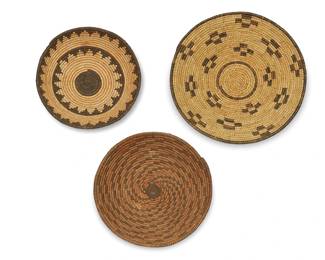 347
A group of Southwest basketry trays
Early 20th century
Three coiled wide baskets comprising an Apache tray with radiating swirling arms issuing from center and rim ticking, (2.25" H x 1.75" Dia.), a smaller Apache tray with two concentric stepped serrated bands (2.25" H x 8.5" Dia.), and a Tohono O'odham/Papago tray with floating checked cross motifs (3" H x 12" Dia.)
3 pieces
Estimate: $300 - $500