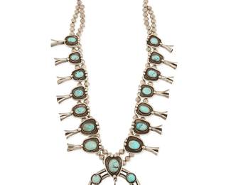 326
A Southwest sterling silver and turquoise squash blossom necklace
Mid/late 20th century
Unmarked
Featuring a large silver two-wire naja with set turquoise plaques and one dangle, and with fourteen matching graduated shadowbox set turquoise blossoms, all suspended from two strands of silver beads
26.5" L x 3.25" H
209.0 grams gross
Estimate: $800 - $1,200