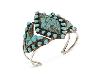 220
A Southwest sterling silver and turquoise cuff bracelet
Late 20th century
Stamped: MM [possibly Michael Mendoza, Navajo/Diné] / Sterling
A two-wire silver cuff designed with three plaques set with angular turquoise and edged with row-set small turquoise cabochons
6.75 total inner C x 2.125" H, including a 1.25" gap
39.2 grams gross
Estimate: $300 - $500