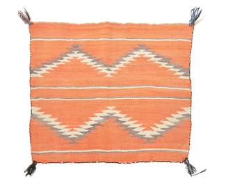 207
A Navajo transitional saddle blanket
Late 19th century, Diné
Woven in red, blue, and cream wool with alternating striped bands and serrated zigzags, with yarn tassels to each corner
24" H x 31" W
Estimate: $800 - $1,200