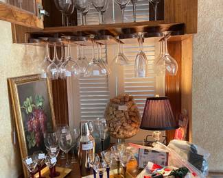 The bar area contains, wine, liquor, champagne glasses, a large brandy glass full of corks, grape art and bar items