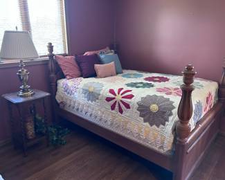 Full bed. Antique side table. Quilts.