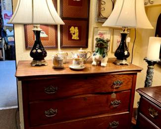 Tiger oak 3 chest of drawers with foo dog figurine and asian tea sets with Asian hand carved art on panels. Black and gold swirl lamps with brass.