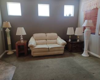 Leather love seat, 2 end tables - one on right has 2 storage drawers. 2 matching lamps on right and 2 floor lamps.
