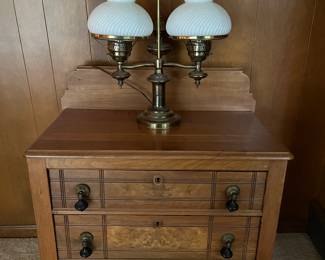 Antique three-drawer chest with teardrop pulls; vintage double-globe brass lamp with milk glass (or similar) shades.