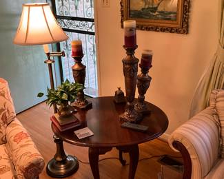 Stand lamp, round table with curved legs, 3 candle sticks with candles, miscellaneous other items on table