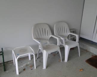 Pair of white plastic chairs, and a nice white table, and more leaves on the ground, and a peak at a rug too